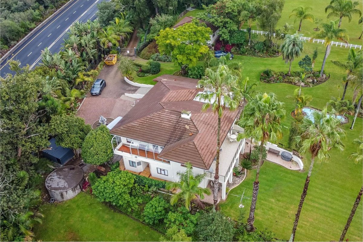 Aerial view of a large residential property featuring a tiled roof, expansive landscaped gardens, a swimming pool, and a paved driveway.