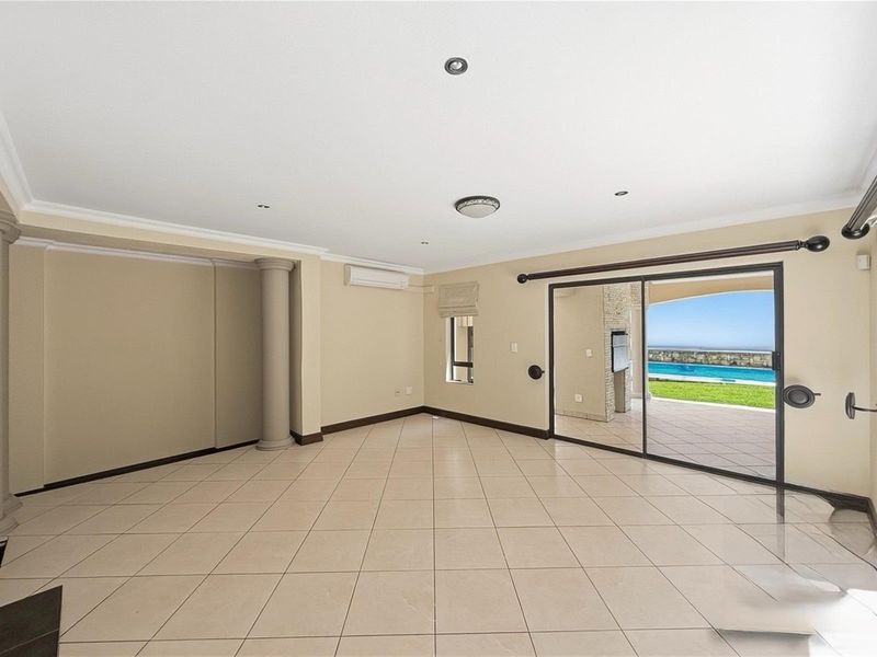 Spacious open-plan living area featuring tiled flooring, recessed lighting, a wall-mounted air conditioning unit, and large sliding glass doors leading to the patio.