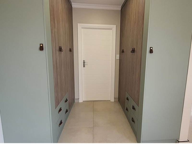 A well-appointed hallway featuring custom built-in cabinetry with a modern two-tone finish, providing ample storage space and a clean, contemporary aesthetic.