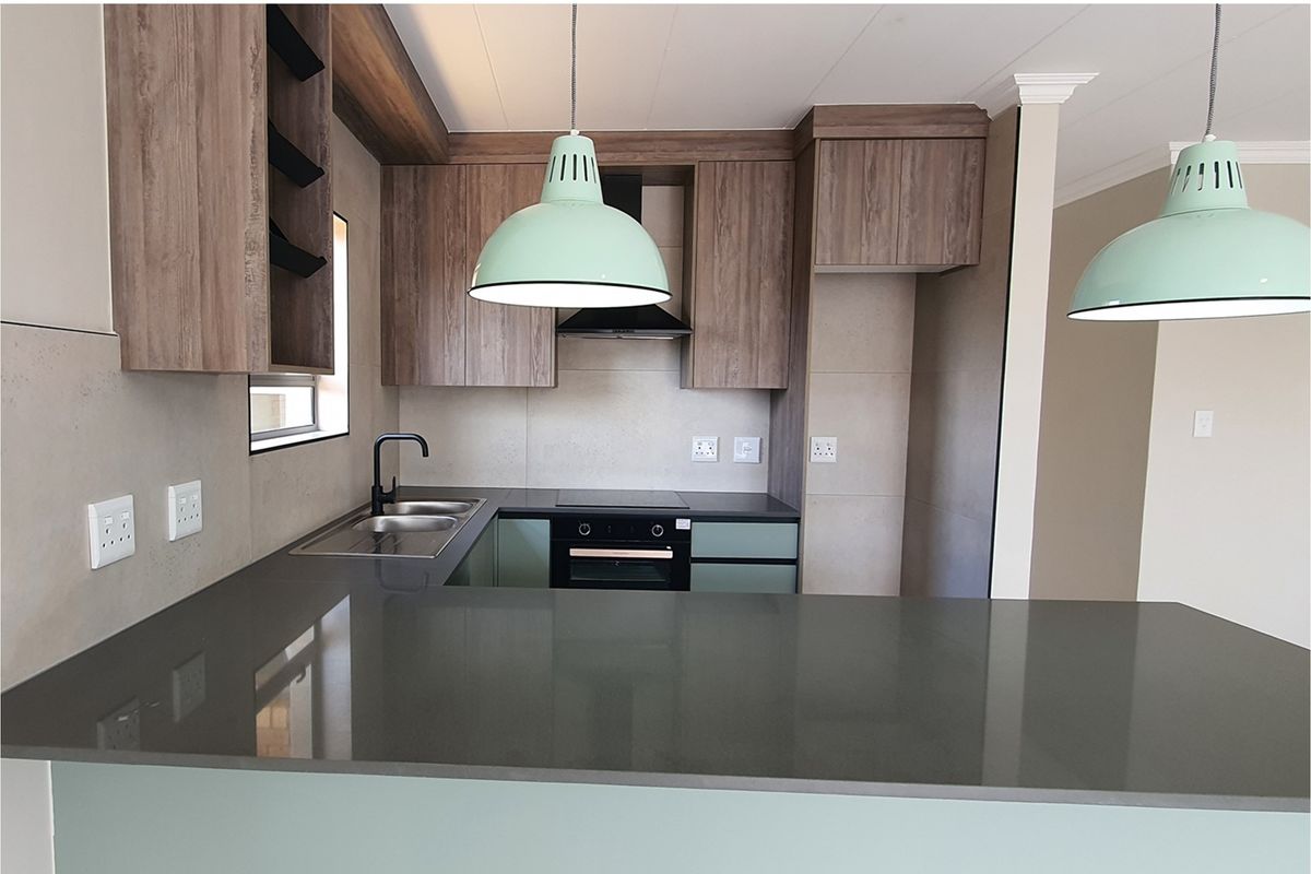 Modern kitchen featuring wood-grain cabinetry, stone countertops, a built-in oven, hob, extractor fan, and a double sink with a contemporary faucet.