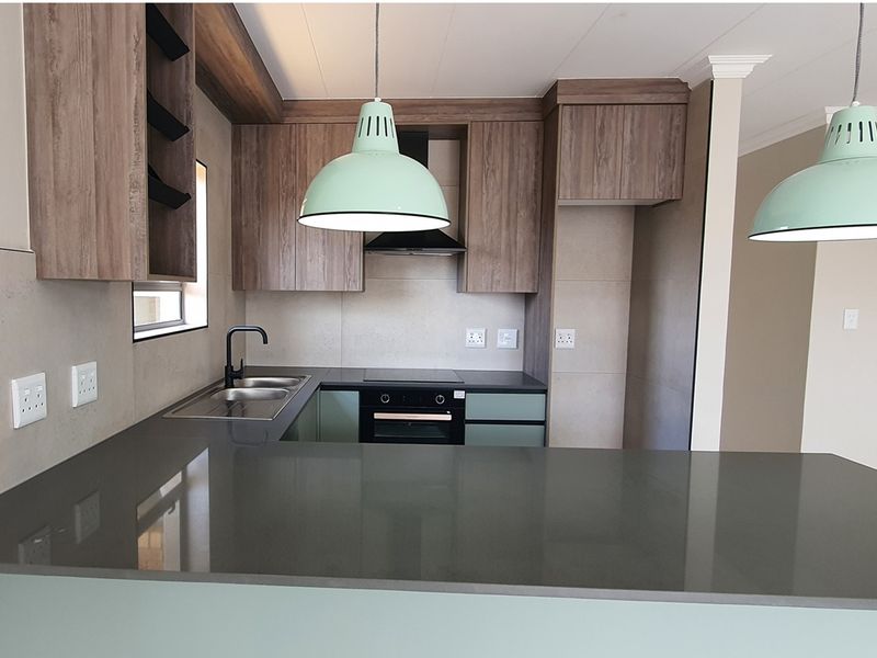 Modern kitchen featuring wood-grain cabinetry, stone countertops, a built-in oven, hob, extractor fan, and a double sink with a contemporary faucet.