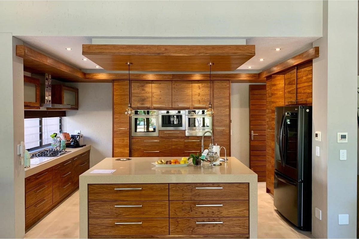 Modern kitchen featuring custom wood cabinetry, a large central island with stone countertop, integrated appliances, and recessed ceiling lighting.