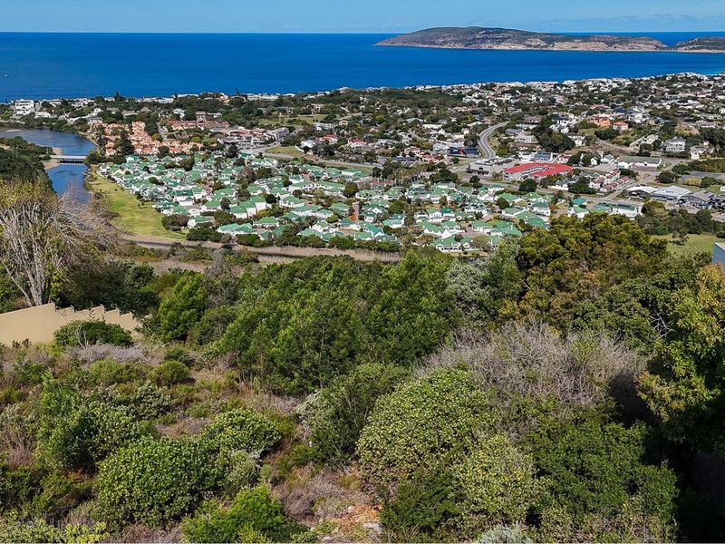 An elevated aerial view showcasing the surrounding coastal landscape, residential neighborhood, and distant ocean horizon.
