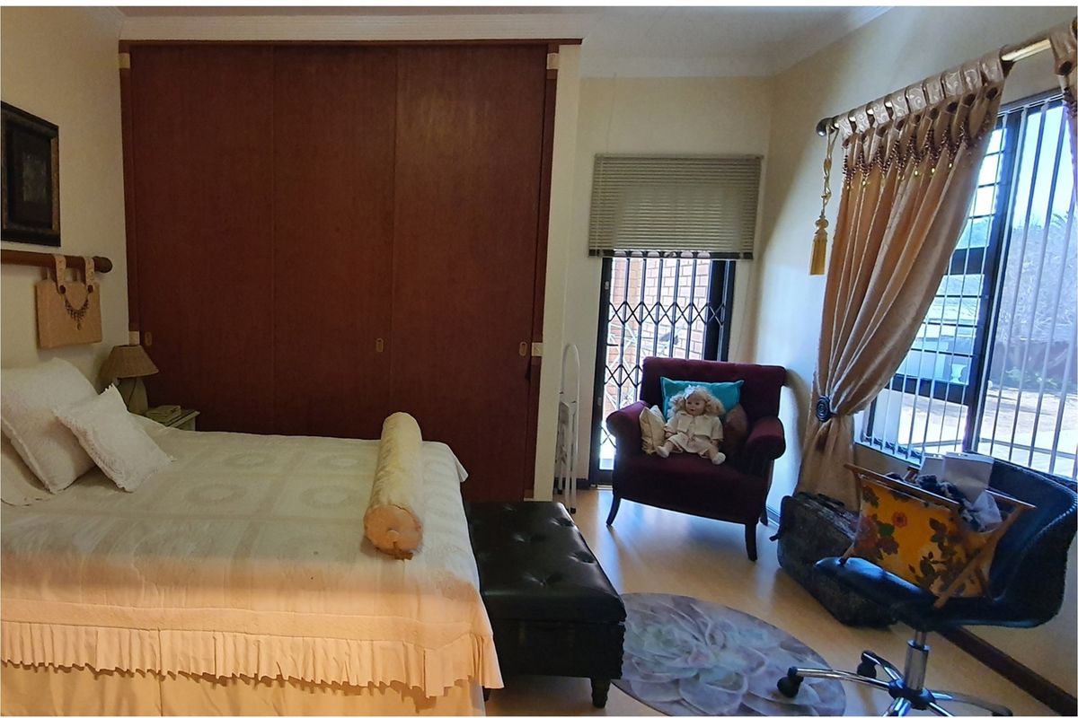 A bedroom featuring built-in wooden cupboards, laminate flooring, and a security gate leading to an outdoor area.
