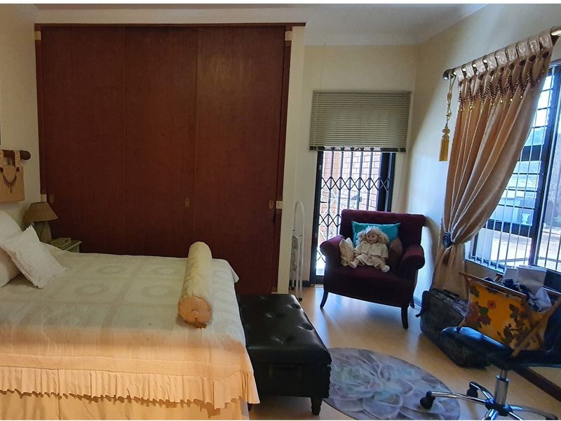 A bedroom featuring built-in wooden cupboards, laminate flooring, and a security gate leading to an outdoor area.