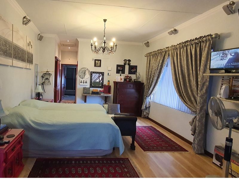 Spacious bedroom featuring light-toned timber flooring, crown molding, and adjustable spotlighting, providing a comfortable and well-lit living space.