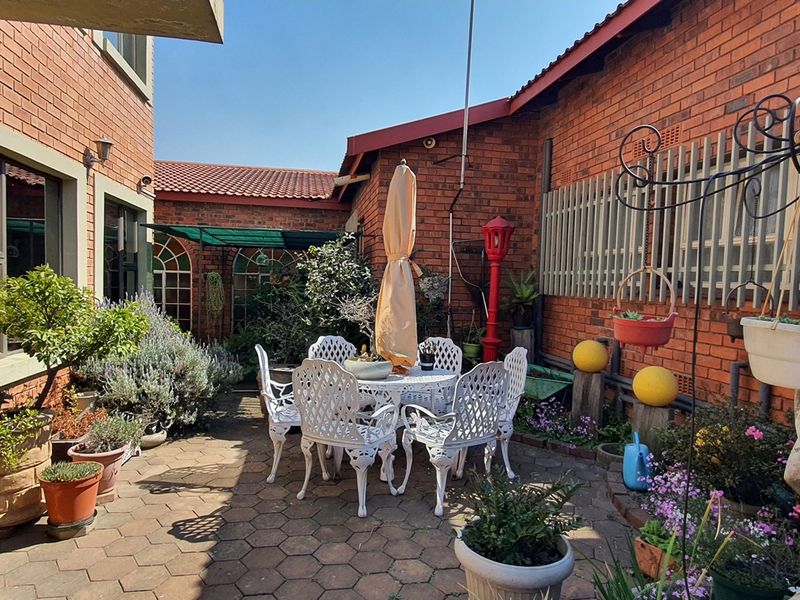 A private, paved courtyard area featuring exposed brick walls and established garden beds, providing a quiet outdoor space for relaxation.