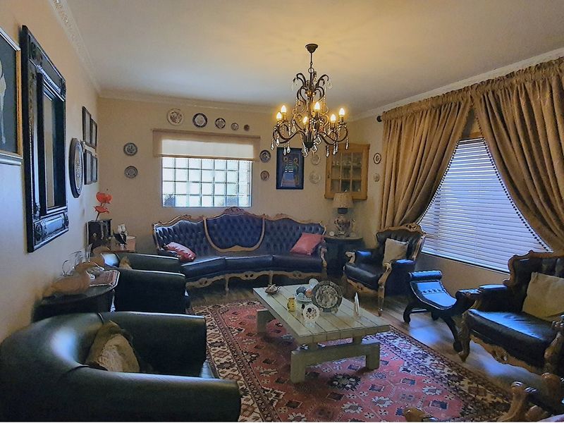 A formal living room featuring a decorative chandelier, glass block window, and crown molding.