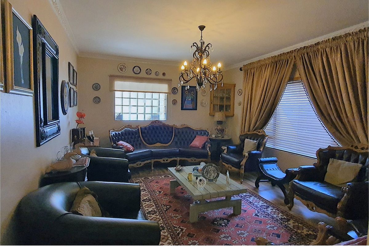 A formal living room featuring a decorative chandelier, glass block window, and crown molding.