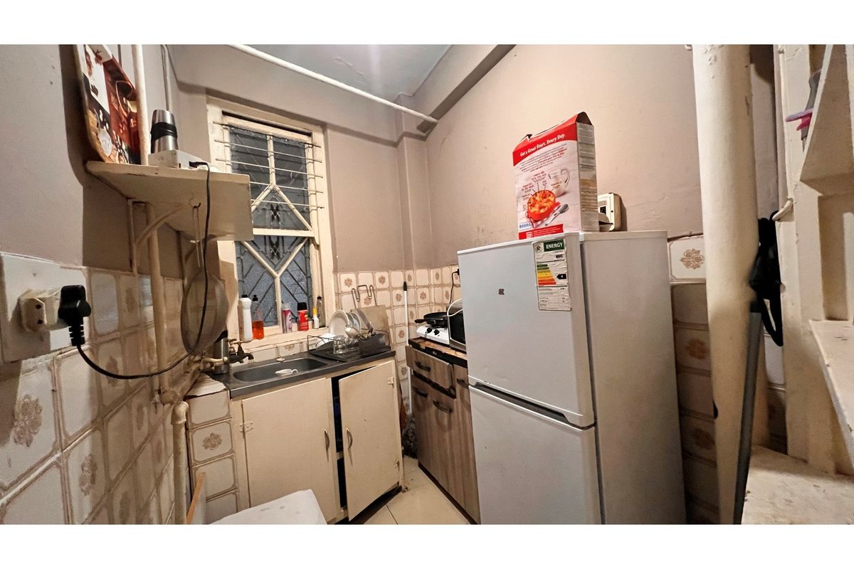 A compact kitchen featuring basic cabinetry, a stainless steel sink, and tiled splashbacks, requiring modernization to improve functionality and aesthetic appeal.