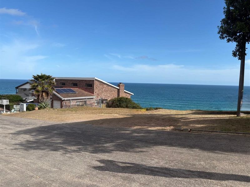 A vacant residential plot offering expansive ocean views, situated in a coastal neighborhood with established surrounding properties.