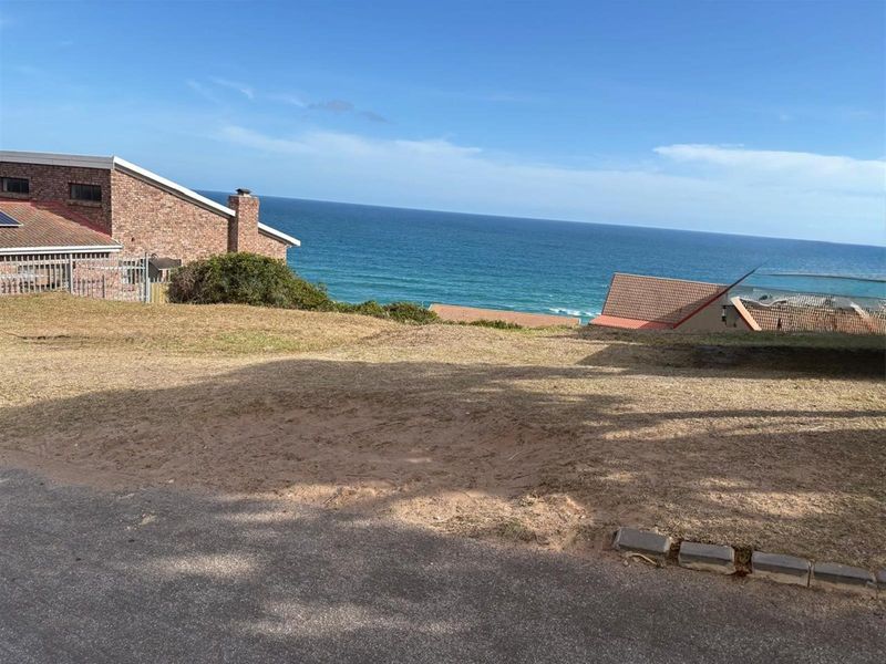 A vacant residential plot offering expansive ocean views, situated in a coastal neighborhood with established surrounding properties.
