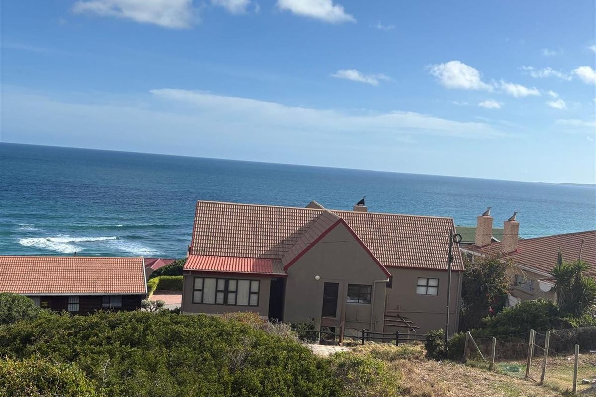 Elevated view of a residential property featuring a tiled roof and coastal backdrop, showcasing the home's position relative to the ocean.
