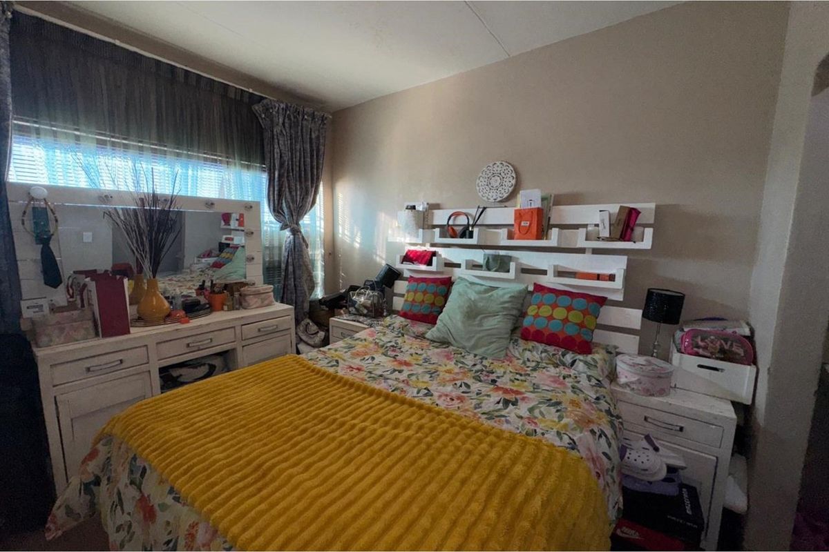 A bedroom featuring a window with blinds and curtains, providing natural light to the space.