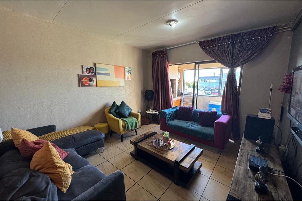 A living room featuring tiled flooring and a sliding glass door that opens to an outdoor balcony area.
