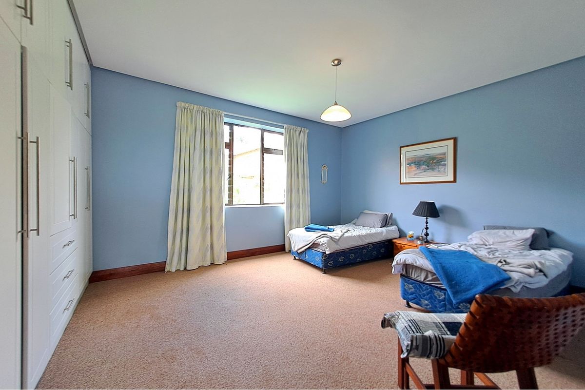 Spacious bedroom featuring built-in cupboards, neutral carpeting, and ample natural light from the window.