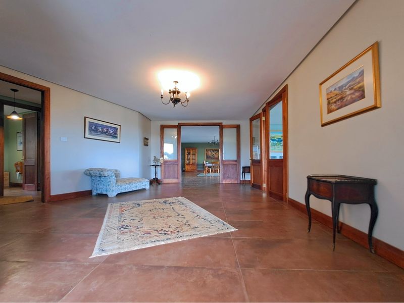 Spacious hallway featuring terracotta tile flooring and timber-framed glass doors connecting to adjacent living areas.