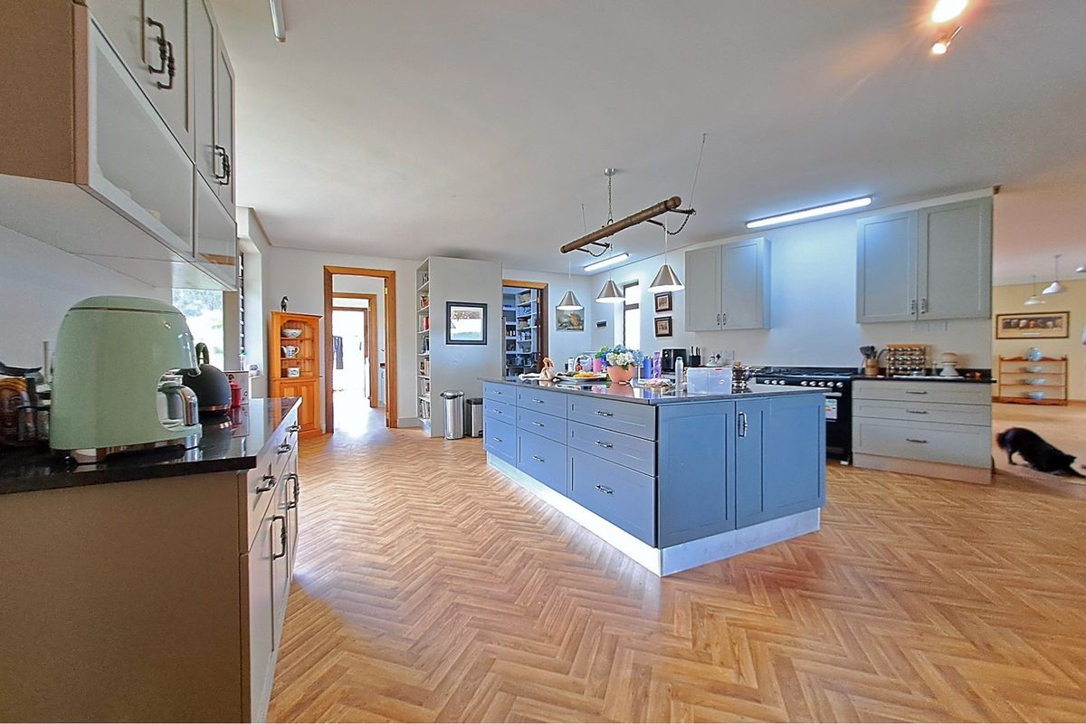 Spacious kitchen featuring a large central island, herringbone timber flooring, modern cabinetry, and a professional-style gas range cooker.