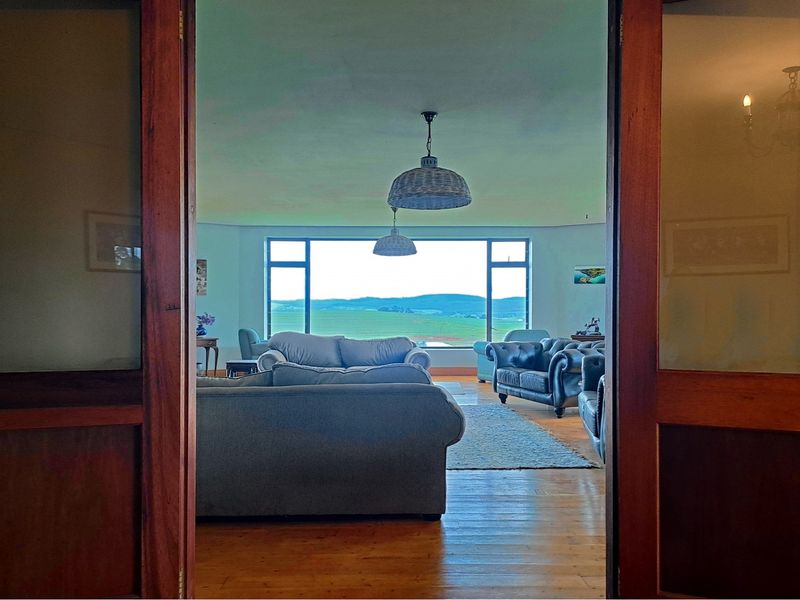 Spacious living room featuring polished hardwood floors, large picture windows with scenic landscape views, and classic timber door frames.