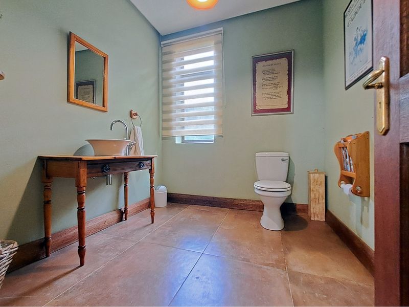 A functional bathroom featuring a ceramic vessel sink on a wooden vanity, tiled flooring, and a standard toilet.