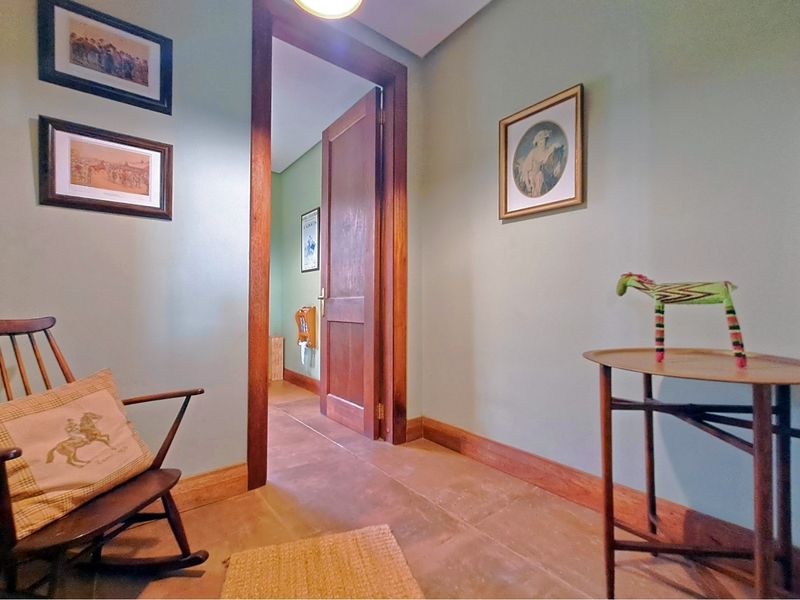 A well-maintained hallway featuring solid timber door frames, skirting boards, and durable stone flooring leading into an adjacent room.