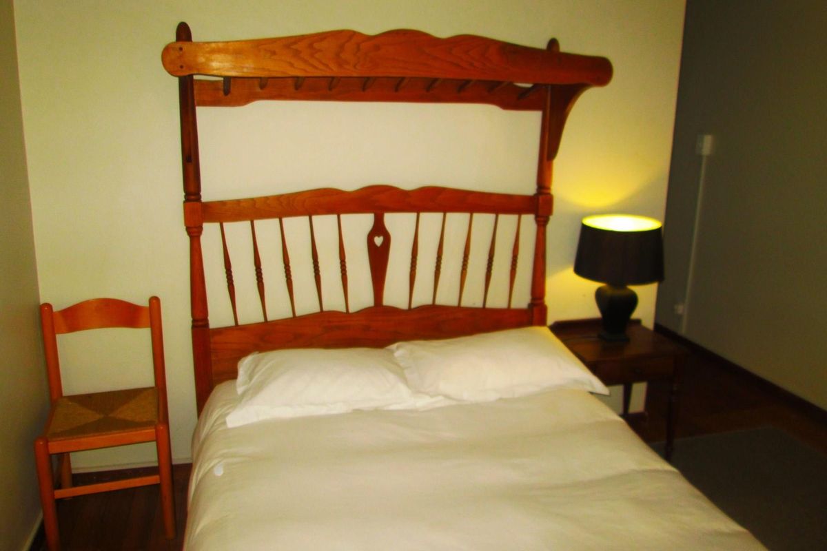 A bedroom featuring wooden flooring and a neutral wall finish, providing a simple and functional sleeping space.
