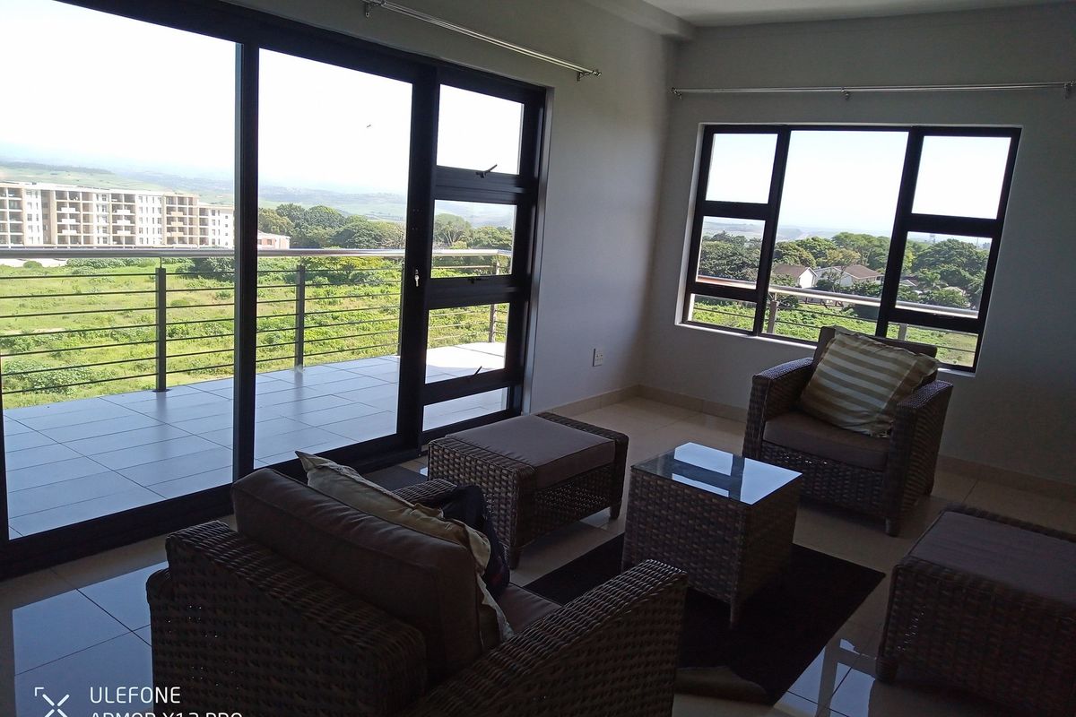 A bright living room featuring large sliding glass doors leading to a balcony, offering expansive views and abundant natural light.