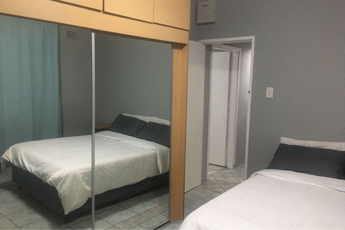 A bedroom featuring tiled flooring and a large built-in mirrored wardrobe, providing ample storage space and a functional layout.