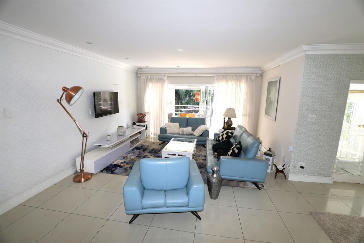 Spacious open-plan living area featuring neutral tiled flooring, recessed ceiling lighting, and sliding glass doors providing access to an outdoor patio space.