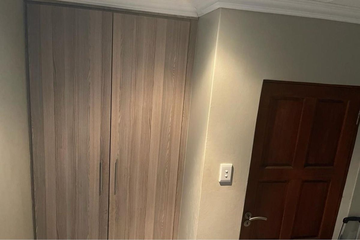 A view of a bedroom featuring built-in wooden cabinetry and a solid timber door with modern hardware.