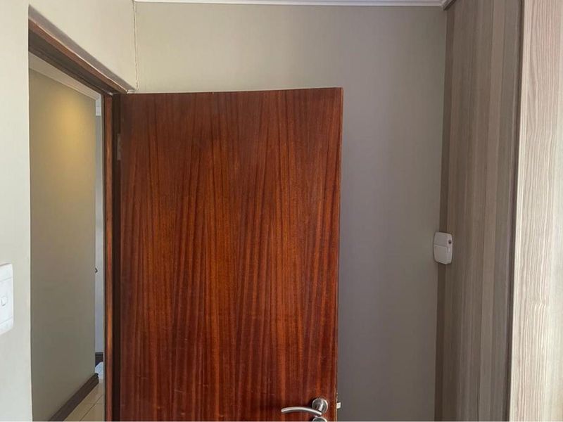 A view of an interior doorway featuring a wooden door and adjacent built-in cabinetry in a neutral-toned hallway.