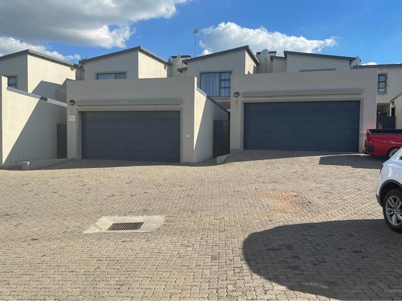 Exterior view of the apartment complex featuring paved driveway access and multiple garage units with modern architectural styling.