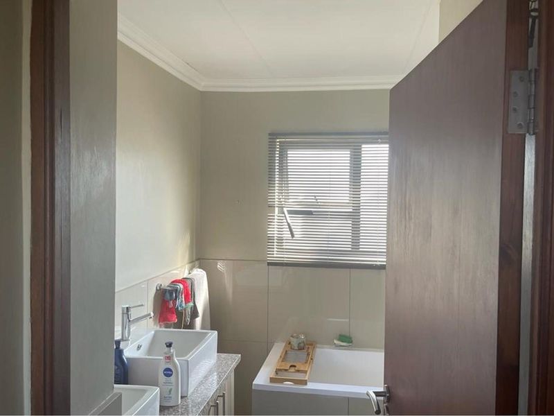 A functional bathroom featuring a modern vessel sink, granite countertop, and a built-in bathtub with a window providing natural light.