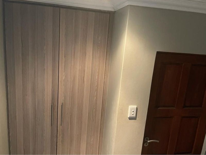 A view of a bedroom featuring built-in wooden cabinetry and a solid timber door with modern hardware.