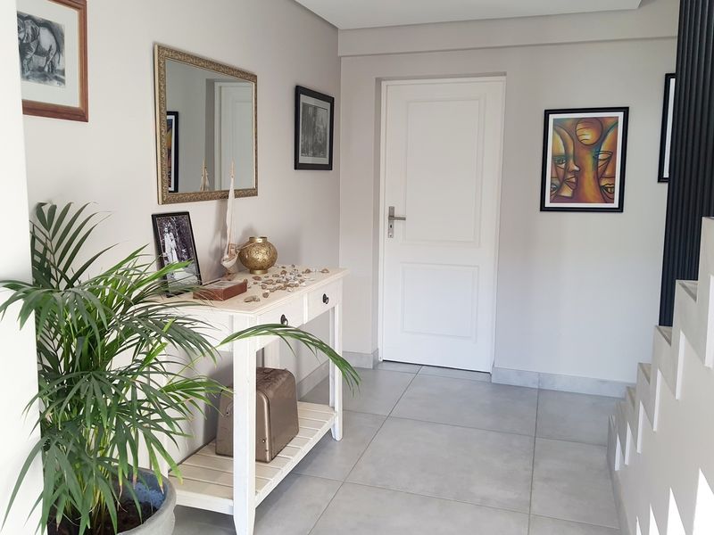 A bright and welcoming entrance hall featuring neutral wall tones, tiled flooring, and a staircase leading to the upper level.