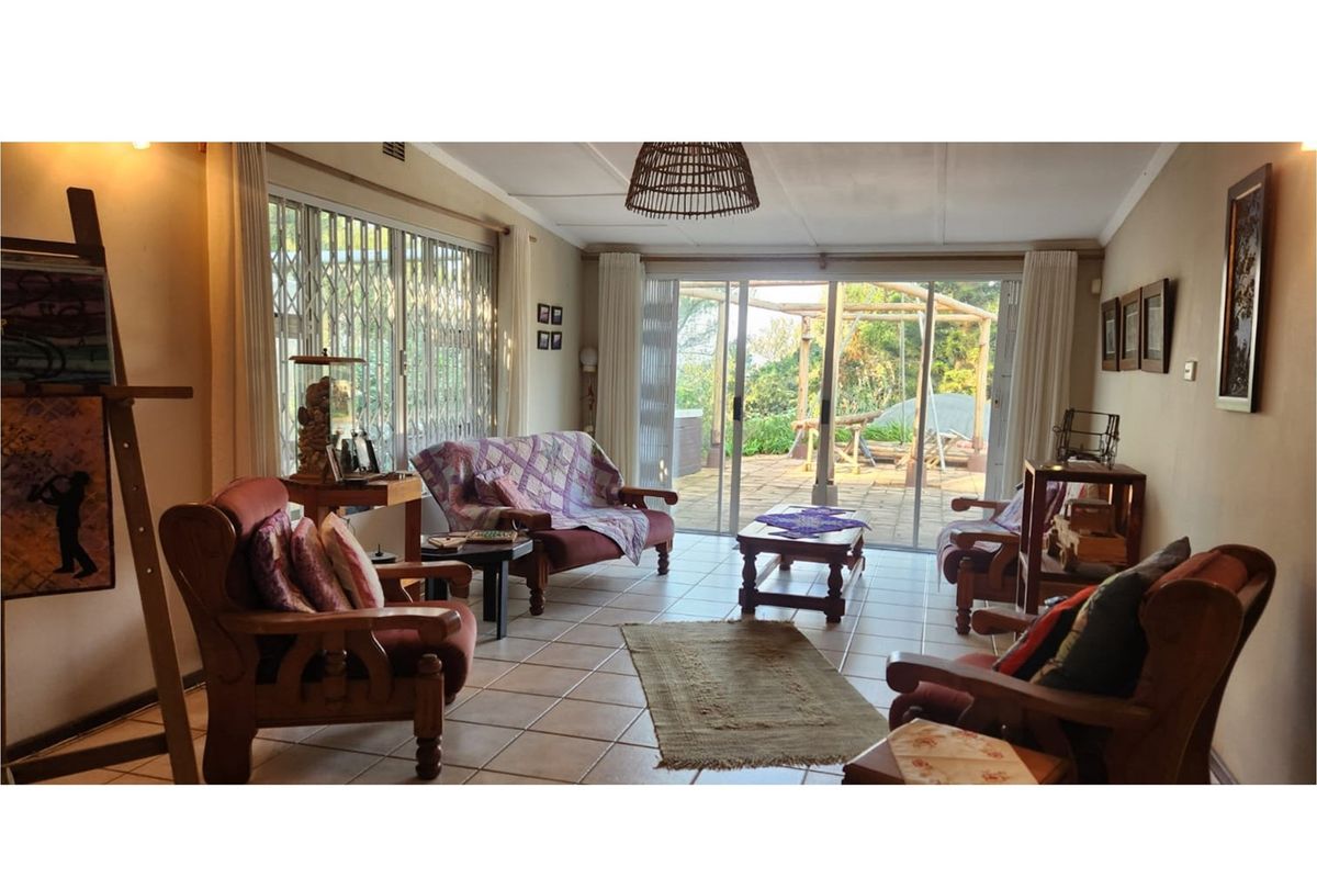 Spacious living room featuring tiled flooring, large sliding glass doors providing natural light, and direct access to an outdoor patio area.