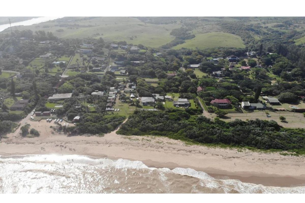 An aerial view of the coastal residential area, showcasing the proximity of the properties to the beach and surrounding natural landscape.