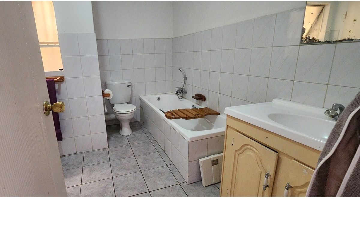 A functional bathroom featuring a standard bathtub, toilet, and vanity basin with tiled walls and flooring.