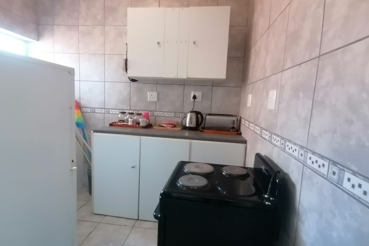 A functional kitchen featuring tiled walls, built-in cabinetry, and a freestanding electric stove.