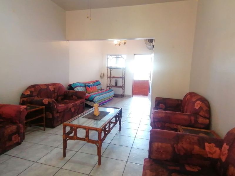 A spacious living area featuring neutral walls and tiled flooring, with direct access to an outdoor patio space.