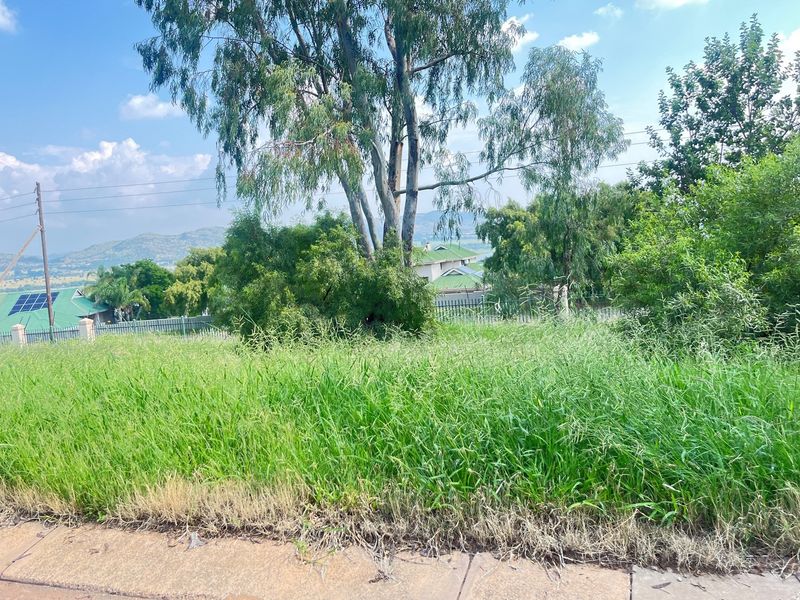 A vacant residential plot featuring established trees and natural grass cover, offering a view of the surrounding landscape and neighboring properties.