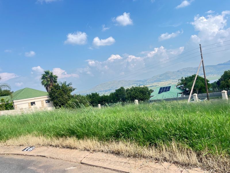 A vacant residential plot featuring established surrounding neighborhood views, mountain vistas, and existing perimeter fencing infrastructure.