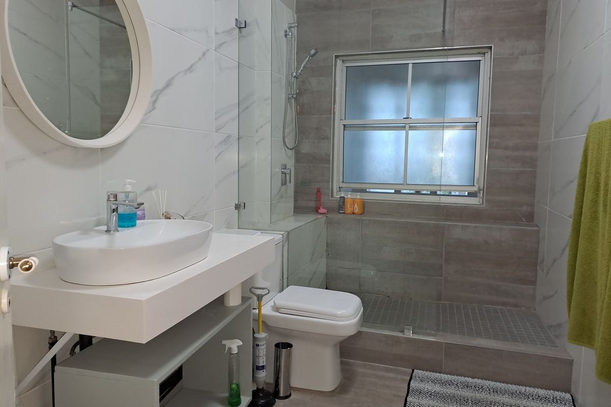 Modern bathroom featuring a floating vanity with vessel sink, glass-enclosed walk-in shower, and contemporary marble-look wall tiling.