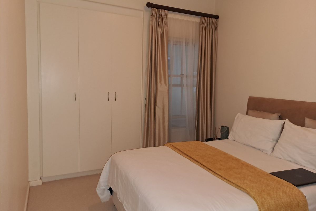A well-maintained bedroom featuring built-in cupboards and neutral carpeting, offering a clean and functional living space.