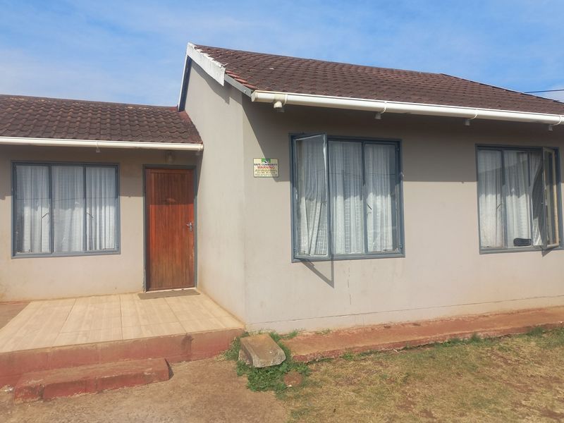 Front elevation of a single-story house featuring a tiled roof, aluminium window frames, and a small concrete entrance patio.