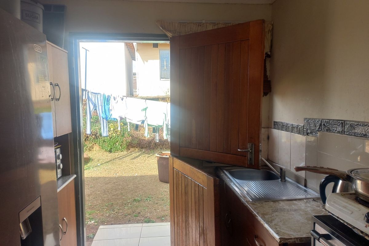 A functional kitchen area featuring built-in cabinetry, a stainless steel sink, and a stable door providing direct access to the rear garden.