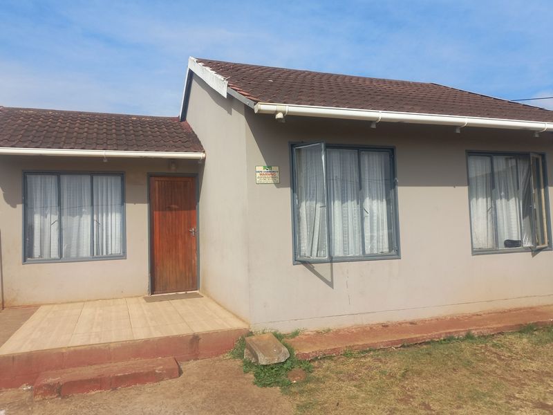 Front elevation of a single-story house featuring a tiled roof, aluminium window frames, and a small tiled entrance porch.