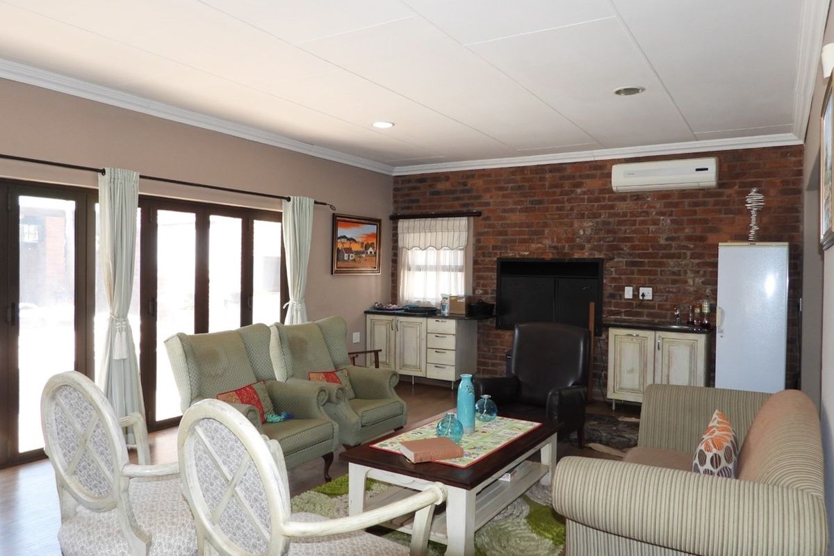 A living room featuring a rustic exposed brick wall, built-in cabinetry, a fireplace, and sliding glass doors providing access to the exterior.