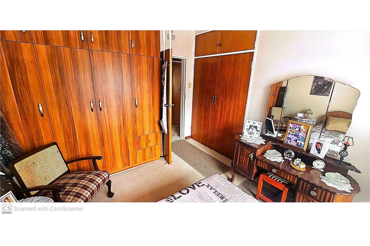 Bedroom featuring extensive built-in wooden cabinetry, carpeted flooring, and a vanity area.