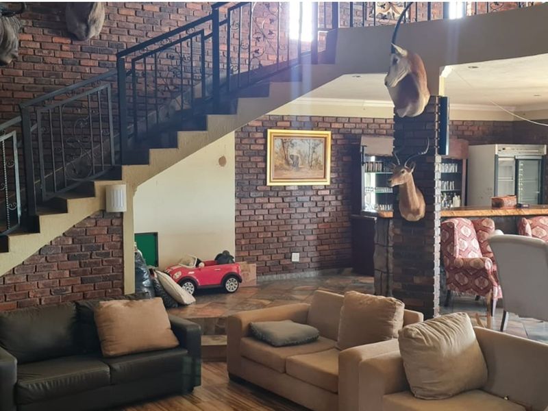 Spacious open-plan living area featuring exposed brick walls, a built-in bar, and a staircase with decorative metal railings.